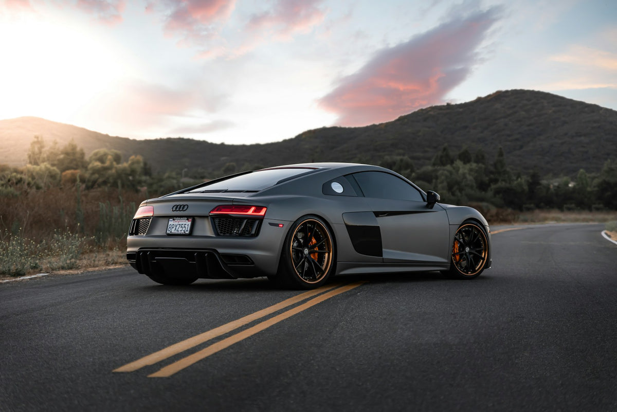Matte grey Audi R8 rear on a mountain road at sunset