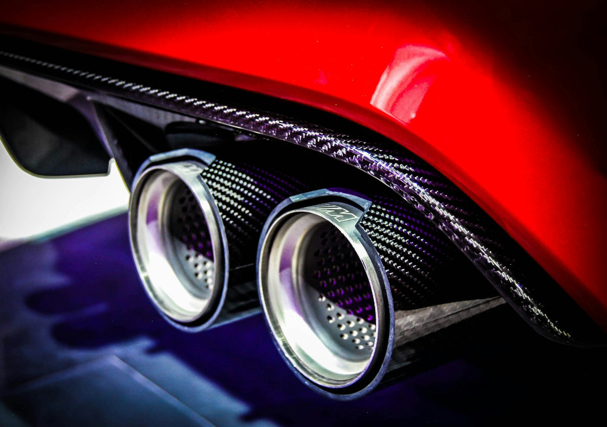 Quad exhaust tips in a carbon fiber diffuser on a red sports car