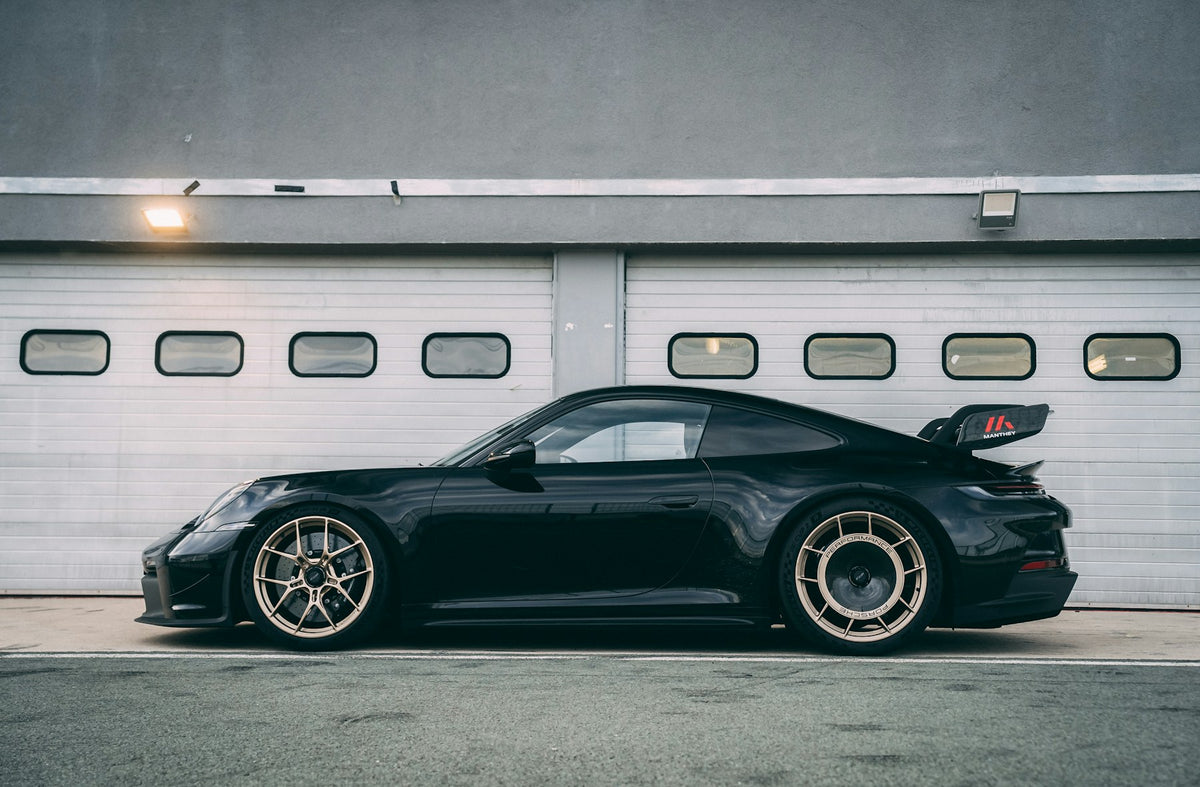 Black Porsche 992 GT3 side profile in front of a garage